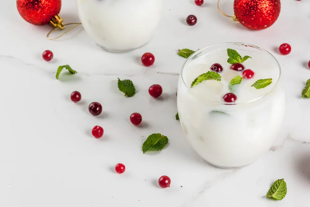 Drink de água de coco com cranberry e hortelã servido com gelo em copo transparente, bebida refrescante e sem álcool em decoração natalina