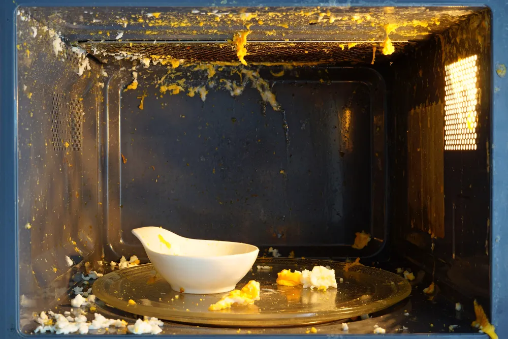 Micro-ondas sujo após tentativa de preparar ovo que estourou, ilustrando erro comum ao cozinhar ovo no micro-ondas sem seguir as orientações corretas.