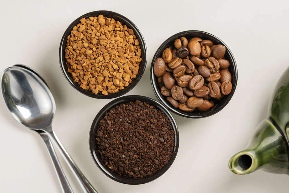 Diferentes tipos de café. Café moído, café instantâneo e grãos de café torrados em pequenas tigelas